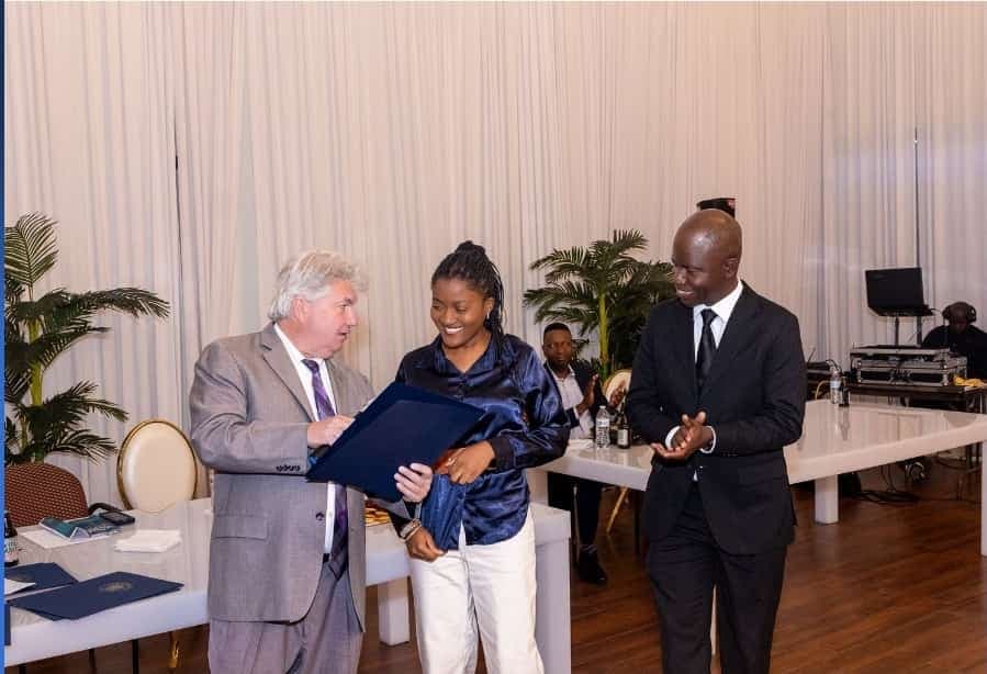 Senator Michael Brady presents a citation folder as Charles Awodu applauds.