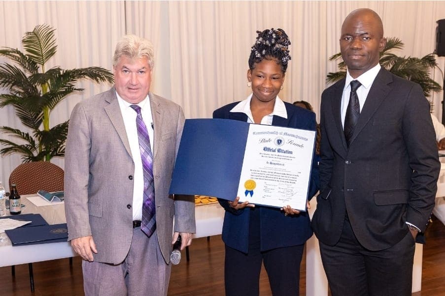 A young leader holds her Official Citation with Senator Michael Brady and Charles Awodu.