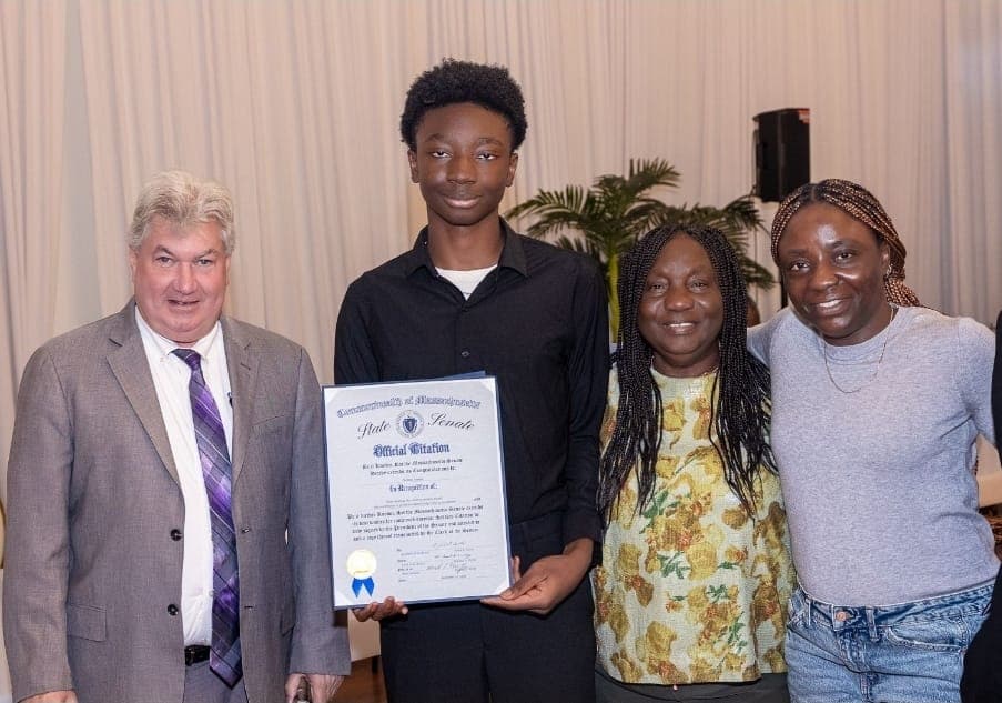 A young author holds his Official Citation with family beside Senator Michael Brady.